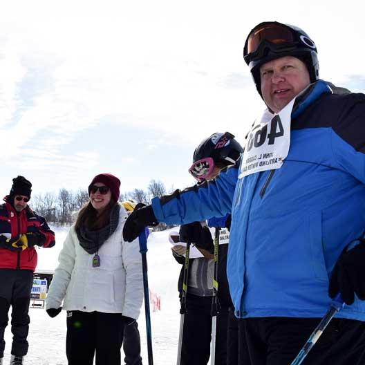 一位穿着滑雪装备的特奥会运动员，旁边是一位太阳城官网的学生志愿者